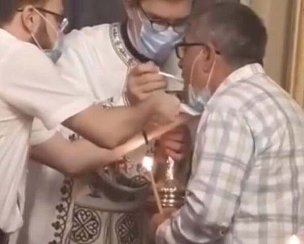 Причастие с использованием пластиковых одноразовых ложечек